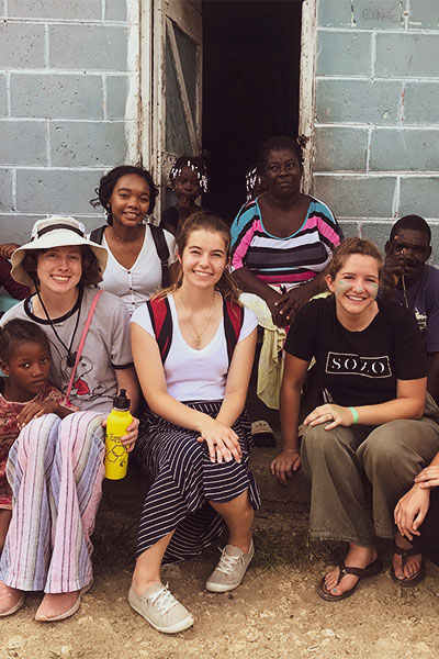 Studente on a missions trip, smiling on a building porch with local people