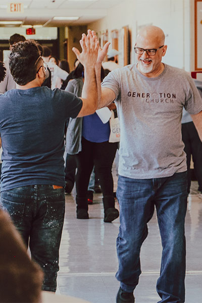 Two men high-fiving in a hallway