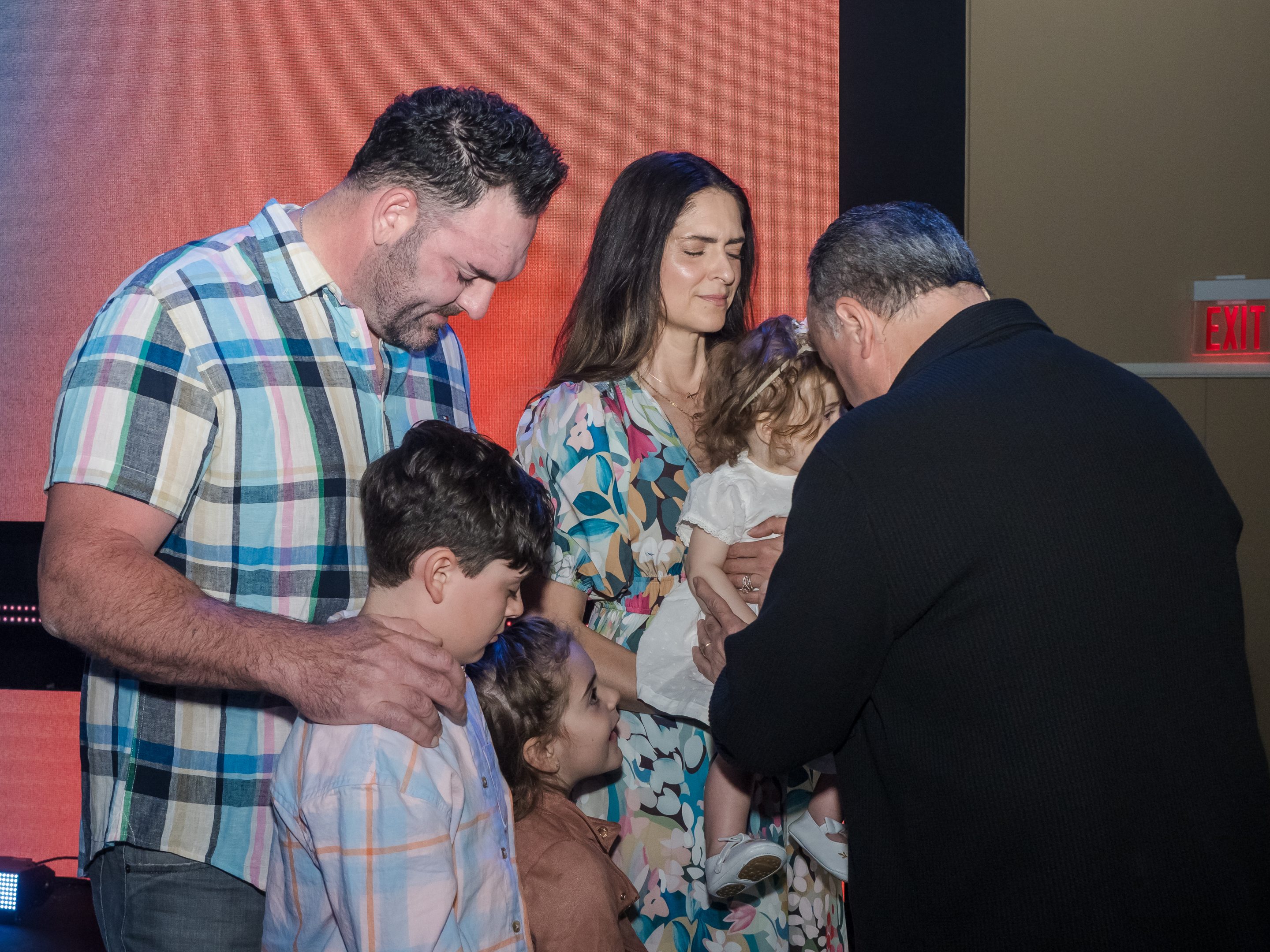 Pastor John Nuzzo praying over a baby during a baby dedication